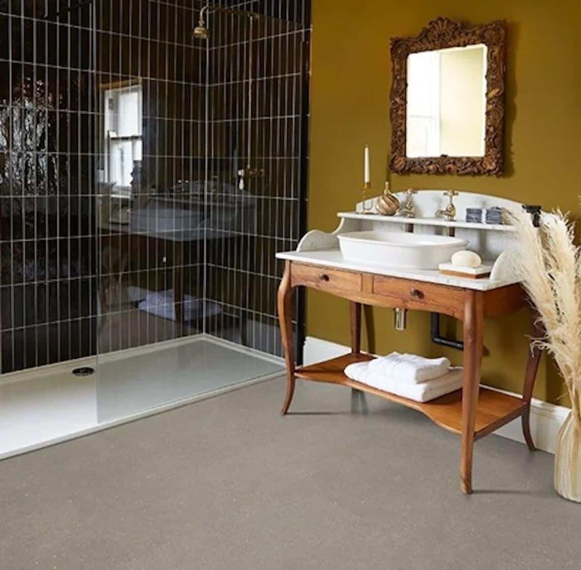 A luxurious, vintage-modern bathroom featuring a dark olive-green wall, a walk-in shower with glossy black subway tiles, and a wooden washstand with a marble top and basin.