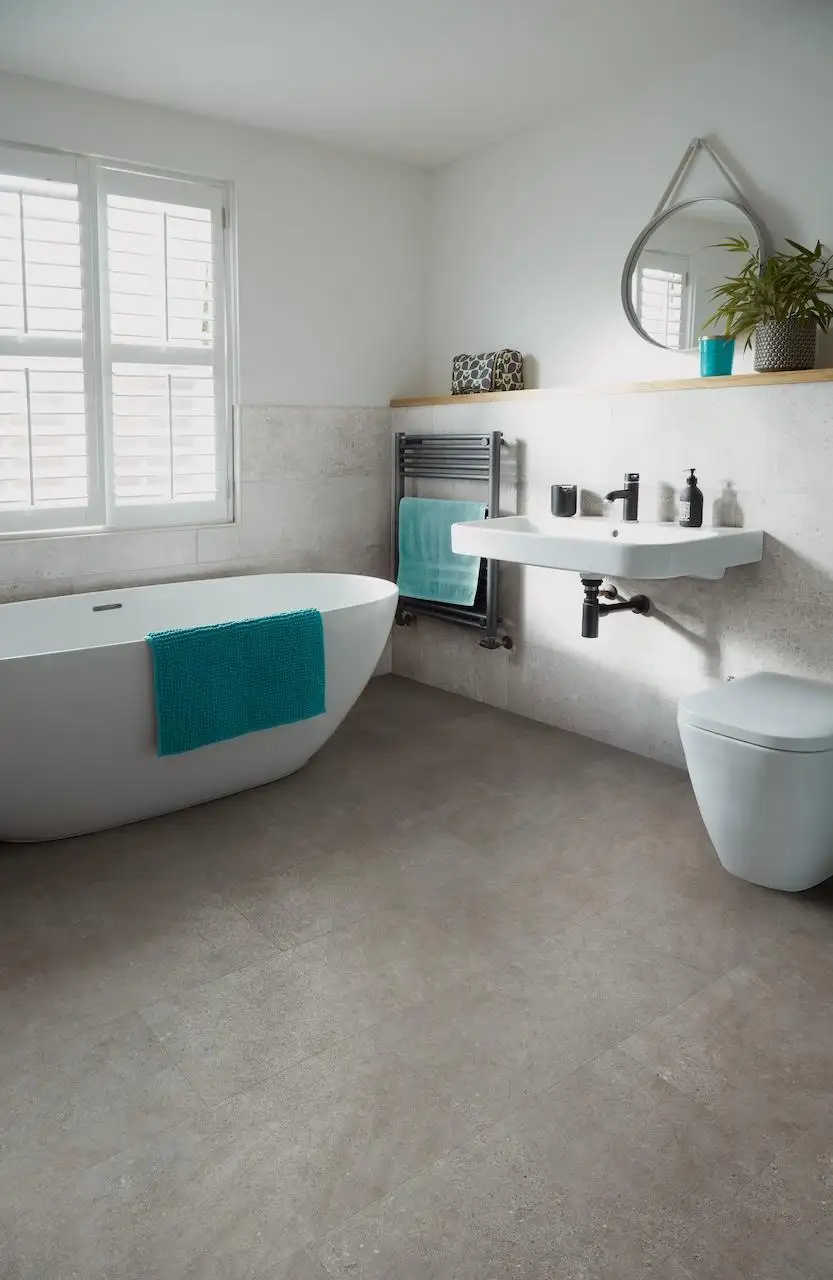 Concrete Look LVT Bathroom Flooring: Waterproof & Durable Luxury Vinyl Tile Light grey concrete look Luxury Vinyl Tile (LVT) from the Camaro range in a modern bathroom with a freestanding white bathtub and wall-mounted sink.