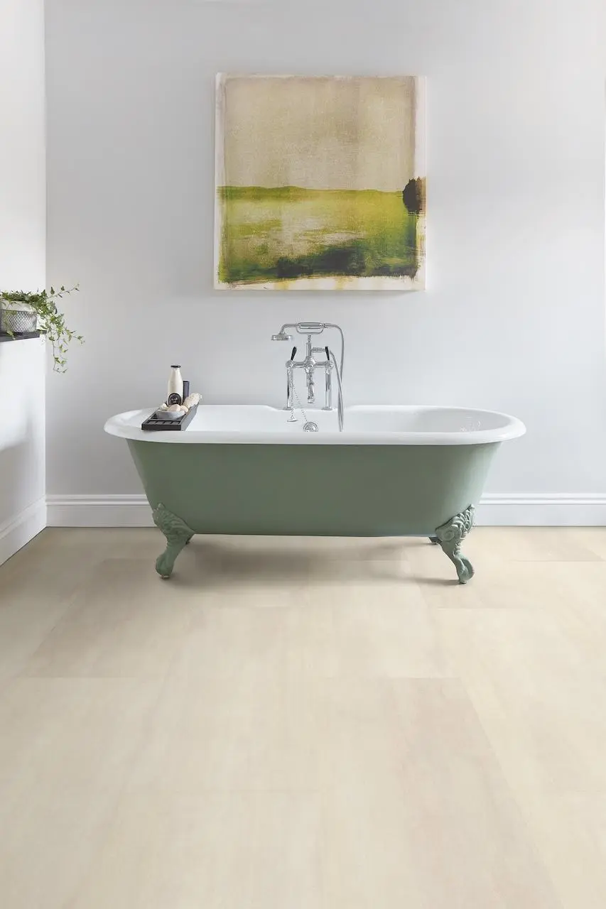 Polyflor Expona Commercial LVT: Durable Light Wood/Stone Effect Bathroom Flooring Light wood or concrete effect Luxury Vinyl Tile (LVT) from the Polyflor Expona Commercial range in a bathroom with a traditional green claw-foot bathtub.