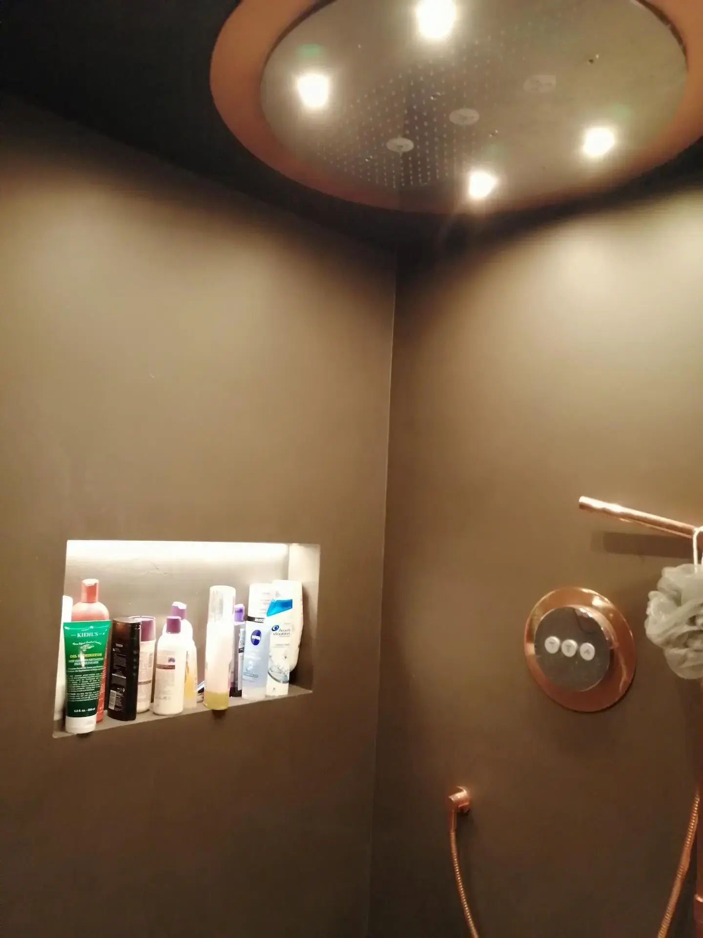 Luxury Dark Microcement Walls with Rose Gold Fixtures and Patterned Floor Dark, seamless microcement shower walls and ceiling paired with a geometric patterned tiled floor and contrasting rose gold/copper shower fixtures in a luxury wet room.